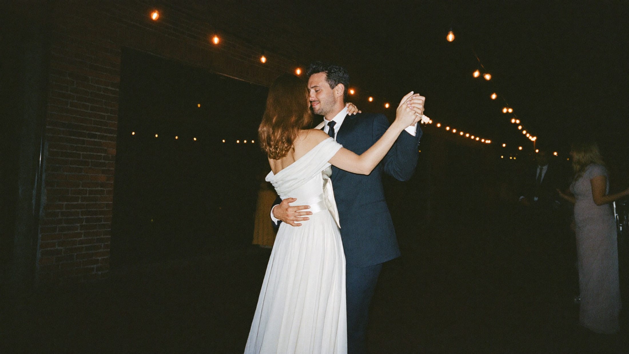 Celien en Vincent dansen samen onder de lichtslingers op hun avondfeest